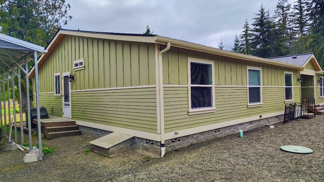 Completed lap and board-and-batten siding with cream corner boards and window trim on a Pacific Northwest home