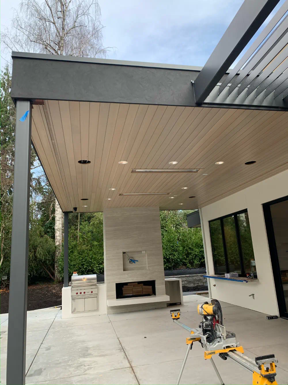 Tongue-and-groove soffit ceiling being installed over a covered patio, miter saw set up on site