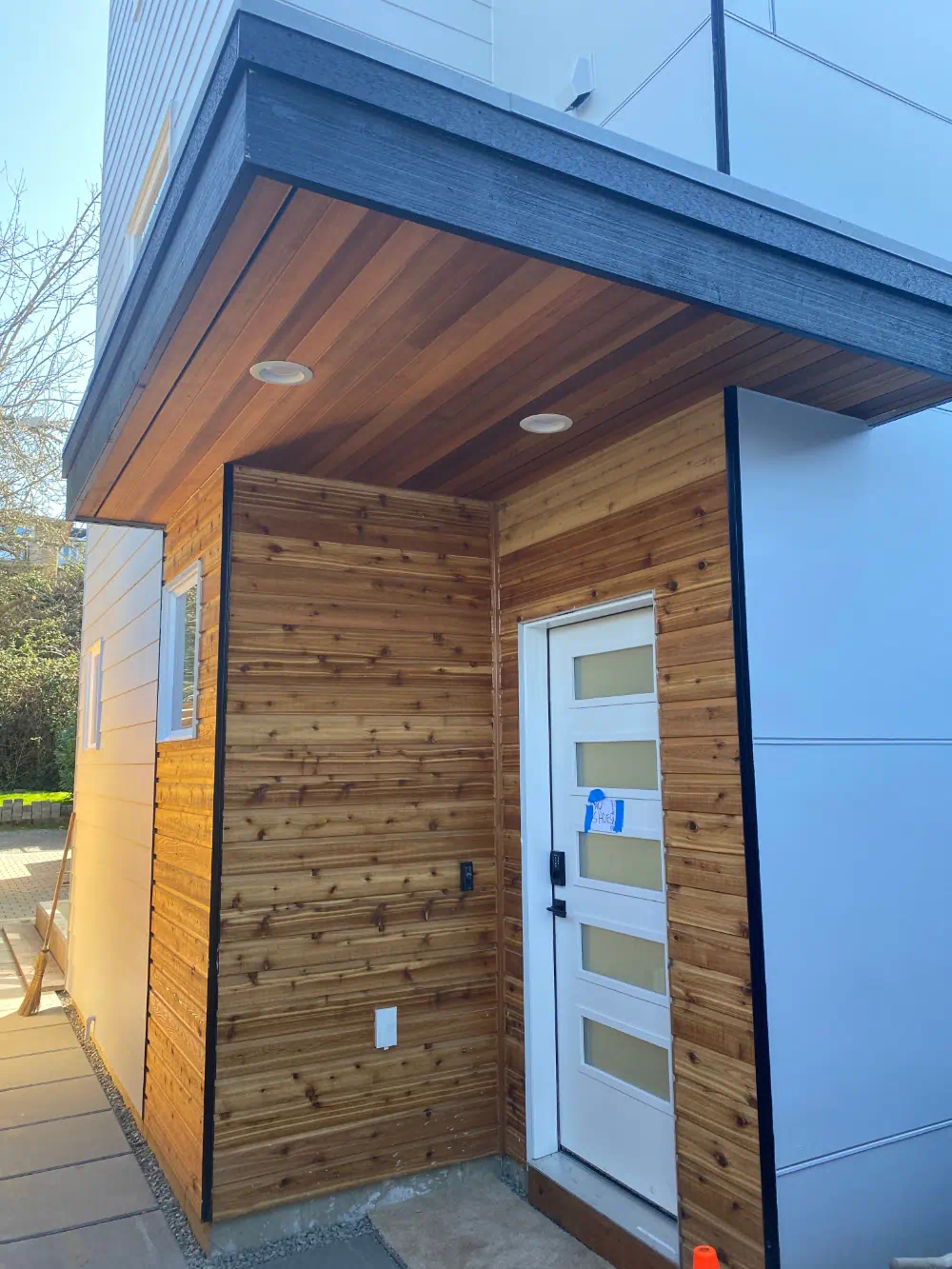 Cedar-clad entry alcove meeting smooth fiber cement panel on a modern Seattle exterior